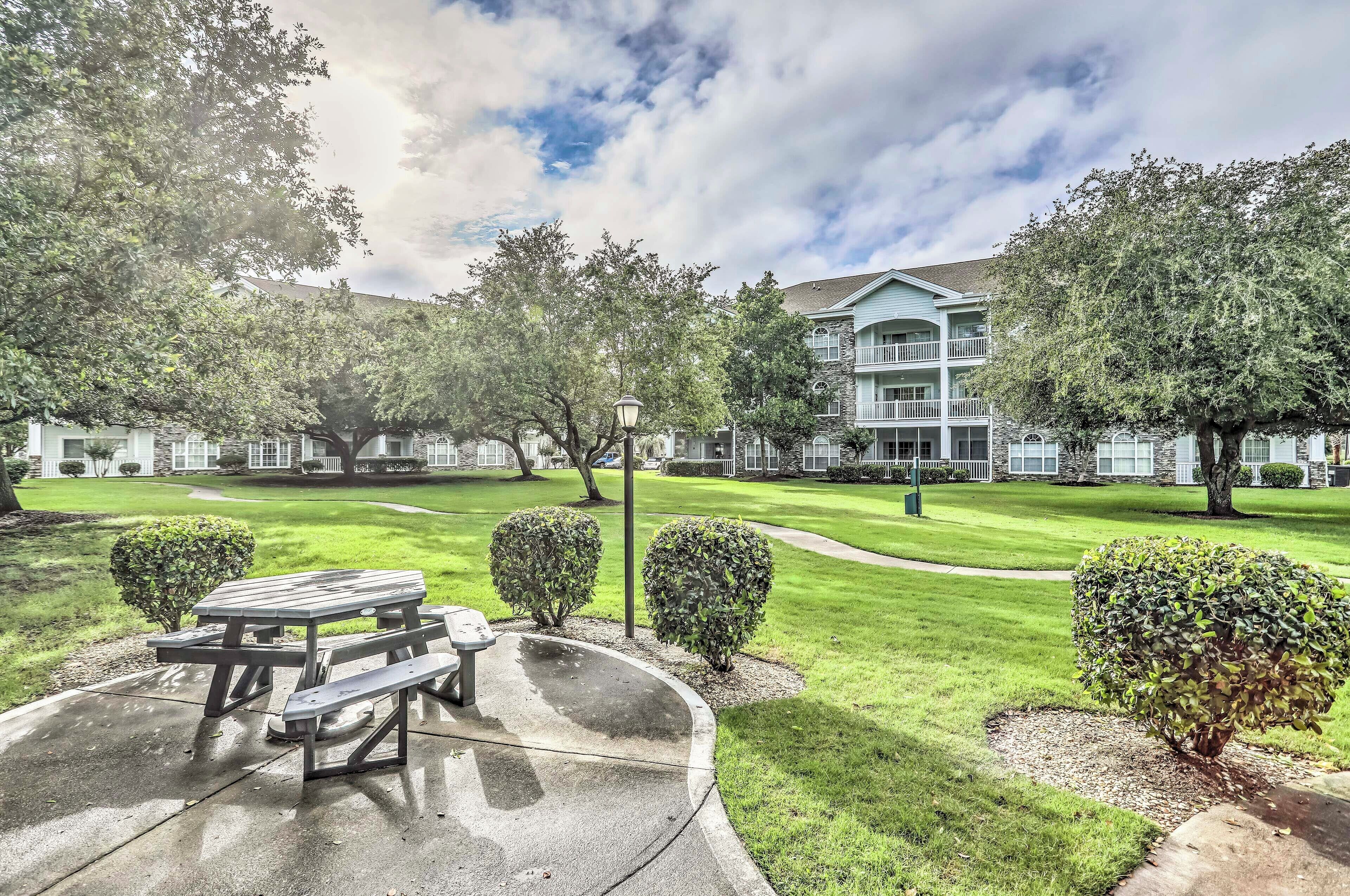 A courtyard with a picnic table, well-maintained grass, and a building with balconies.