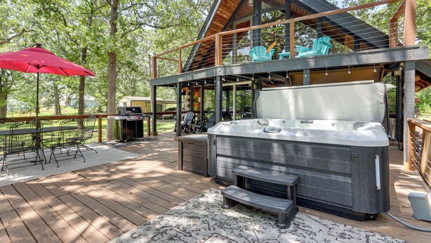 A hot tub on a wooden deck with outdoor furniture and a covered seating area. - Furnished Deck + Lake Access: Fairland Log Cabin (Fairland)