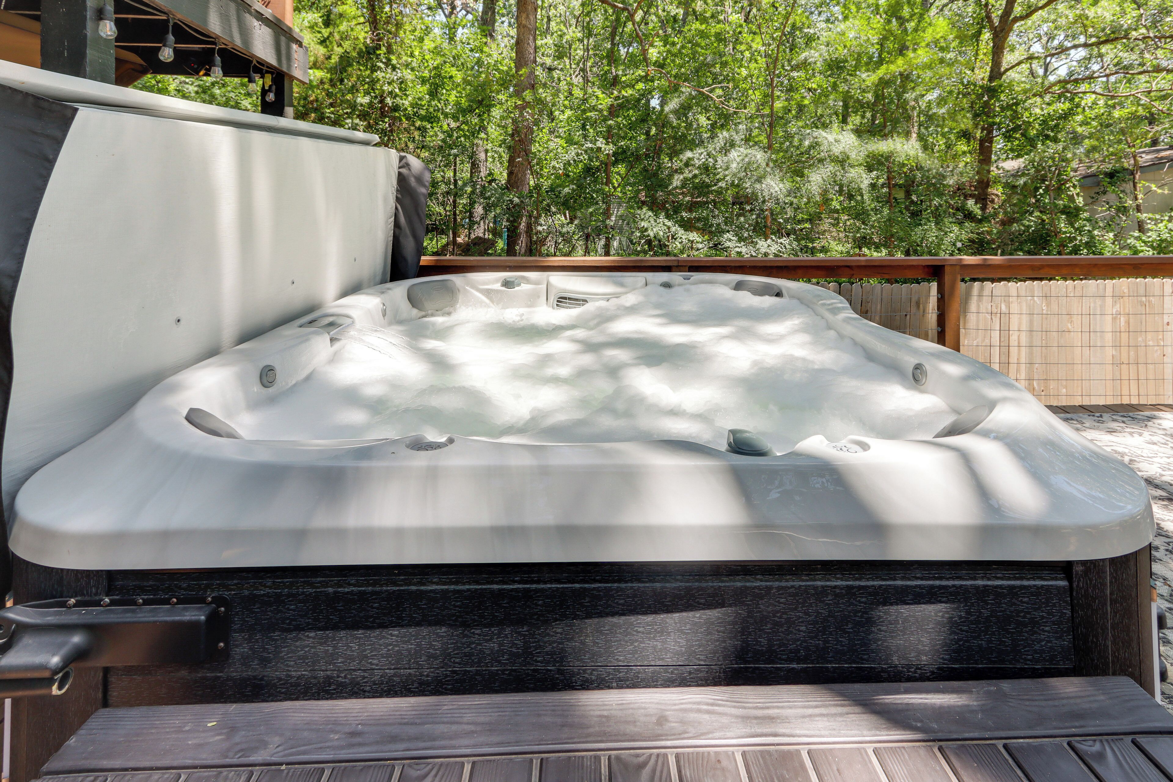 Ein Whirlpool mit einer Holzterrasse und einem Holzzaun im Hintergrund.