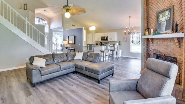 A spacious living room with a sectional sofa, a gray armchair, and a staircase leading to an upper level. - 7 Mi to Beach: Pet-friendly Home in Port Orange! (Port Orange)