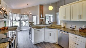 A modern kitchen with white cabinets, granite countertops, and a built-in dishwasher. - 7 Mi to Beach: Pet-friendly Home in Port Orange! (Port Orange)