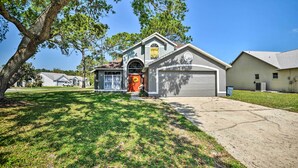 A two-story house with a garage, a large tree in front, and a well-maintained lawn. - 7 Mi to Beach: Pet-friendly Home in Port Orange! (Port Orange)