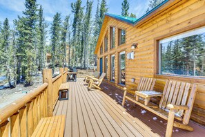 Une terrasse en bois avec des sièges d’extérieur, entourée de grands arbres.