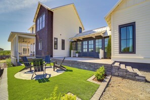 Une maison moderne à deux étages, dotée d’un patio, d’un espace salon extérieur et d’une pelouse bien entretenue.