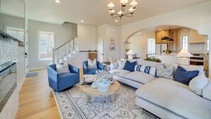 A spacious living room with a large sectional sofa, a coffee table, and a chandelier. - Charming Carlton Landing Home: Walk to Lake! (Eufaula)
