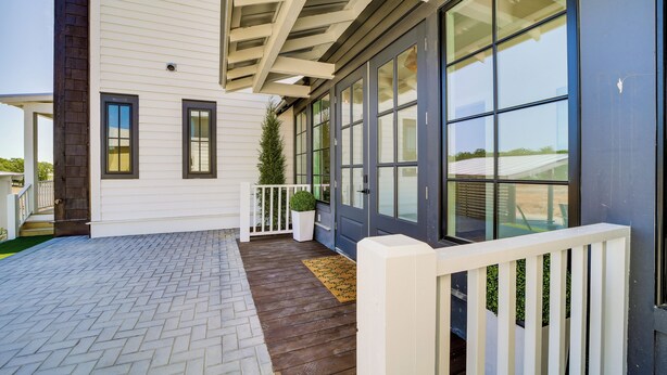 A modern house with a covered porch, large windows, and a white fence. - Charming Carlton Landing Home: Walk to Lake! (Eufaula)