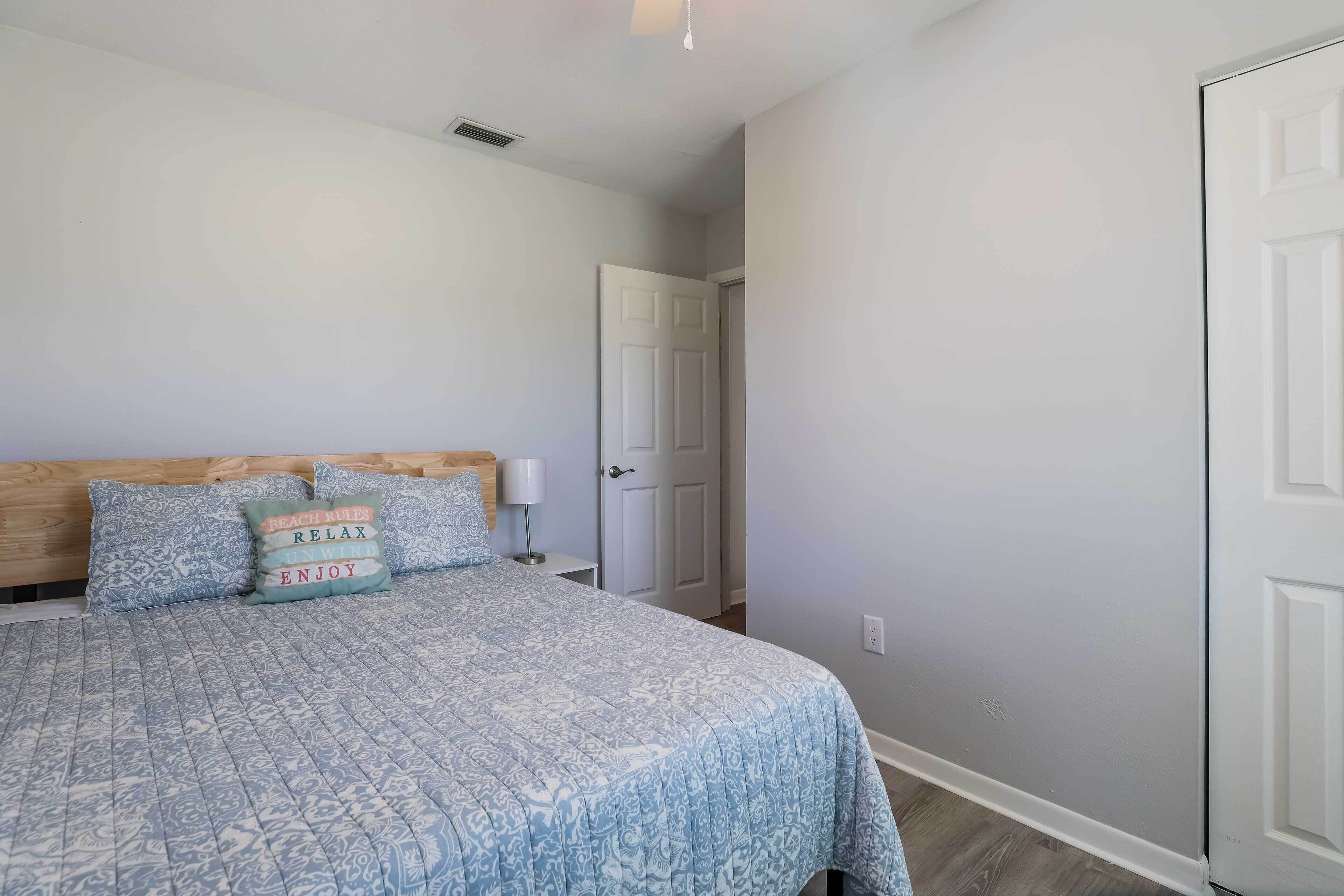 A bedroom with a bed, pillows, a nightstand, and a door.