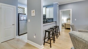 Una cocina moderna con armarios blancos, un refrigerador de acero inoxidable y una zona con taburete de bar.