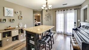 A spacious kitchen with a granite countertop, bar stools, and a piano.