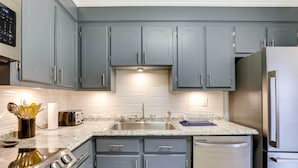 A modern kitchen with grey cabinets, stainless steel appliances, and a granite countertop. - North Charleston Vacation Rental Near Cooper River (North Charleston)