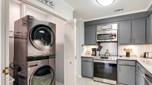 A compact kitchen with a microwave, oven, and a double washer-dryer unit. - North Charleston Vacation Rental Near Cooper River (North Charleston)