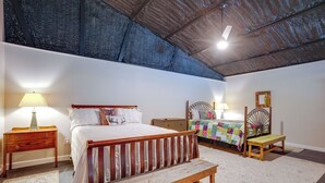 A bedroom with a wooden bed, bedside tables, a bench, a nightstand, and a mirror. - Point Blank Vacation Rental w/ Large Patio! (Pointblank)