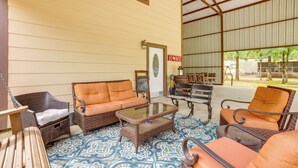 A covered patio with wicker furniture, a glass coffee table, and a patterned floor. - Point Blank Vacation Rental w/ Large Patio! (Pointblank)