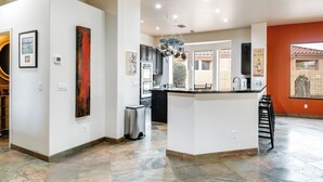 A spacious kitchen with a central island, modern appliances, and artwork on the walls. - Luxe Couples Retreat w/ Pool & Outdoor Kitchen! (Phoenix)