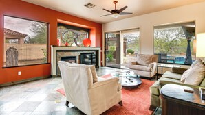 A spacious living room with a fireplace, comfortable seating, and large windows offering views of the outdoors. - Luxe Couples Retreat w/ Pool & Outdoor Kitchen! (Phoenix)