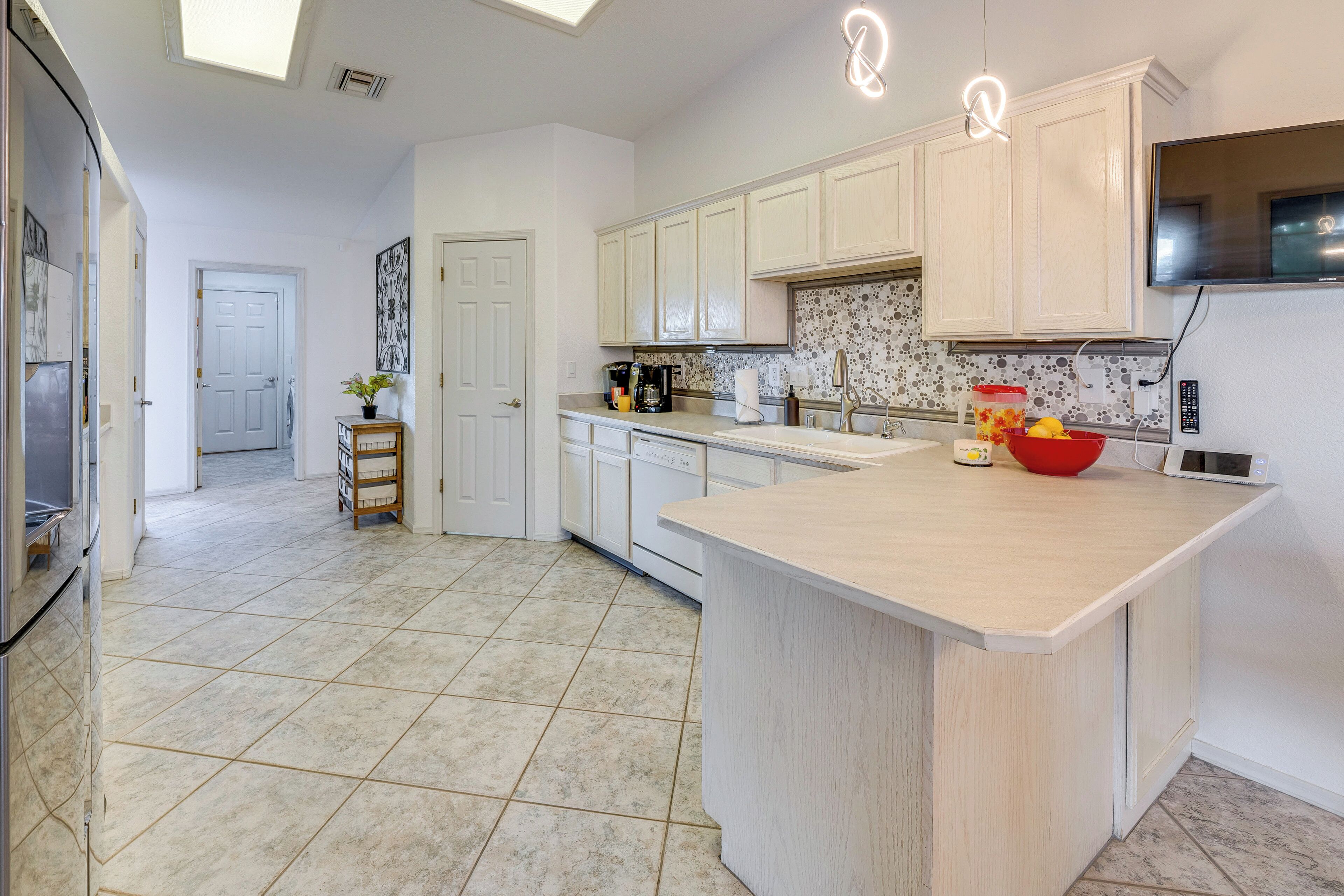 A modern kitchen with white cabinets, a large island, and a tiled floor.