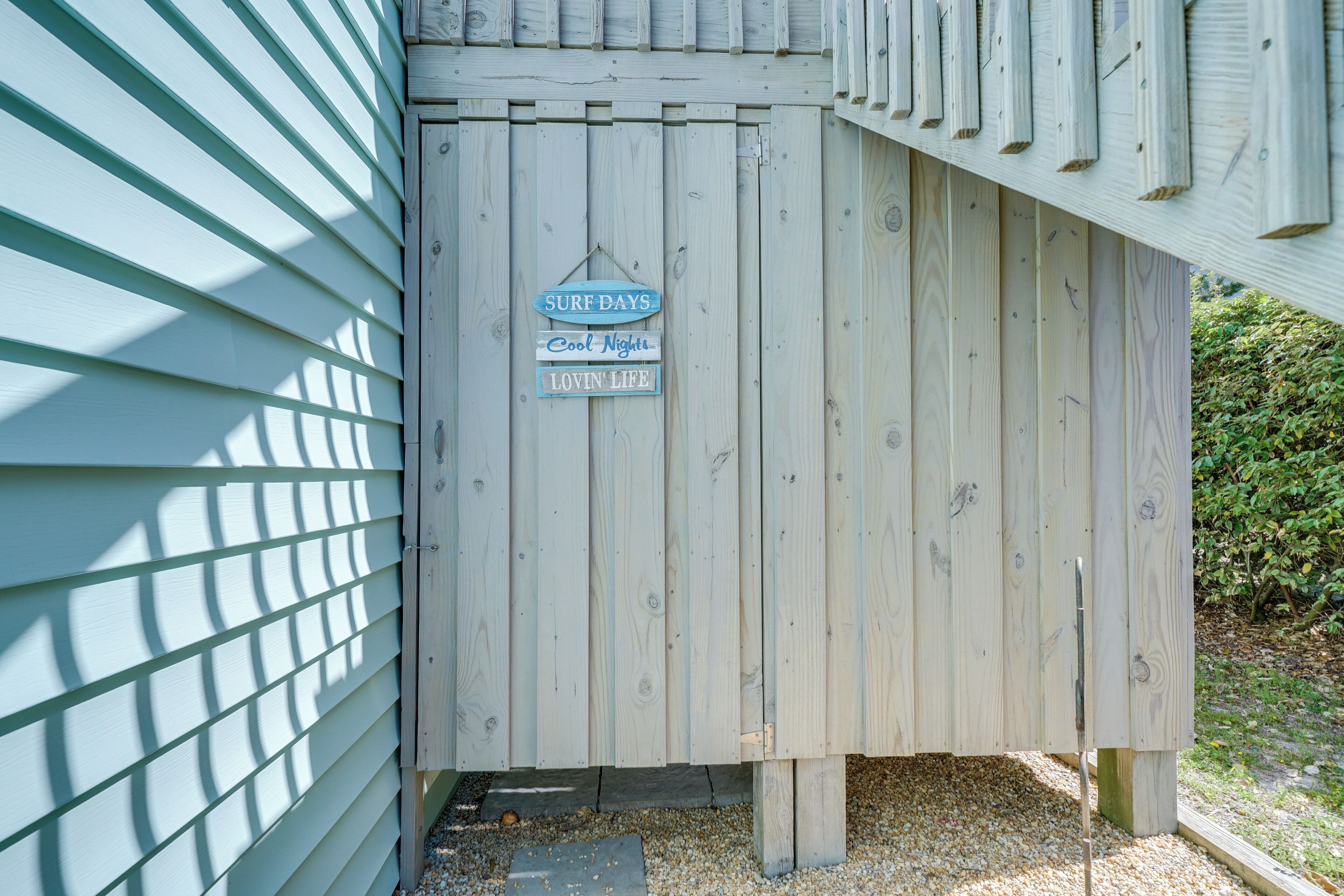 A wooden fence with a sign that reads "Surf Days," "Cool Nights," and "Lovin' Life."