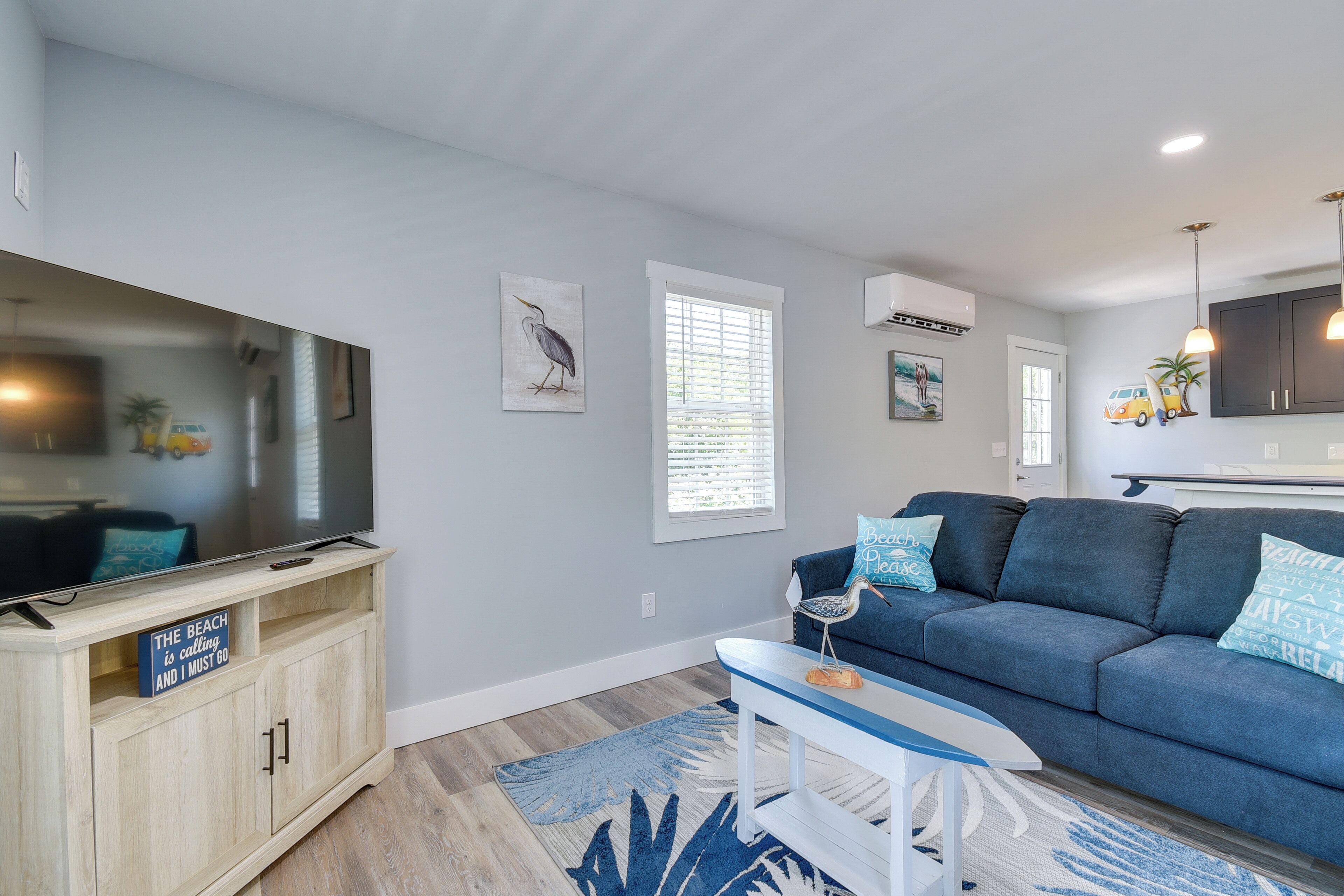 A modern living room with a blue sofa, a flat-screen TV, and a wooden cabinet.