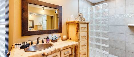 A bathroom with a wooden vanity, a large mirror, and a glass shower enclosure.