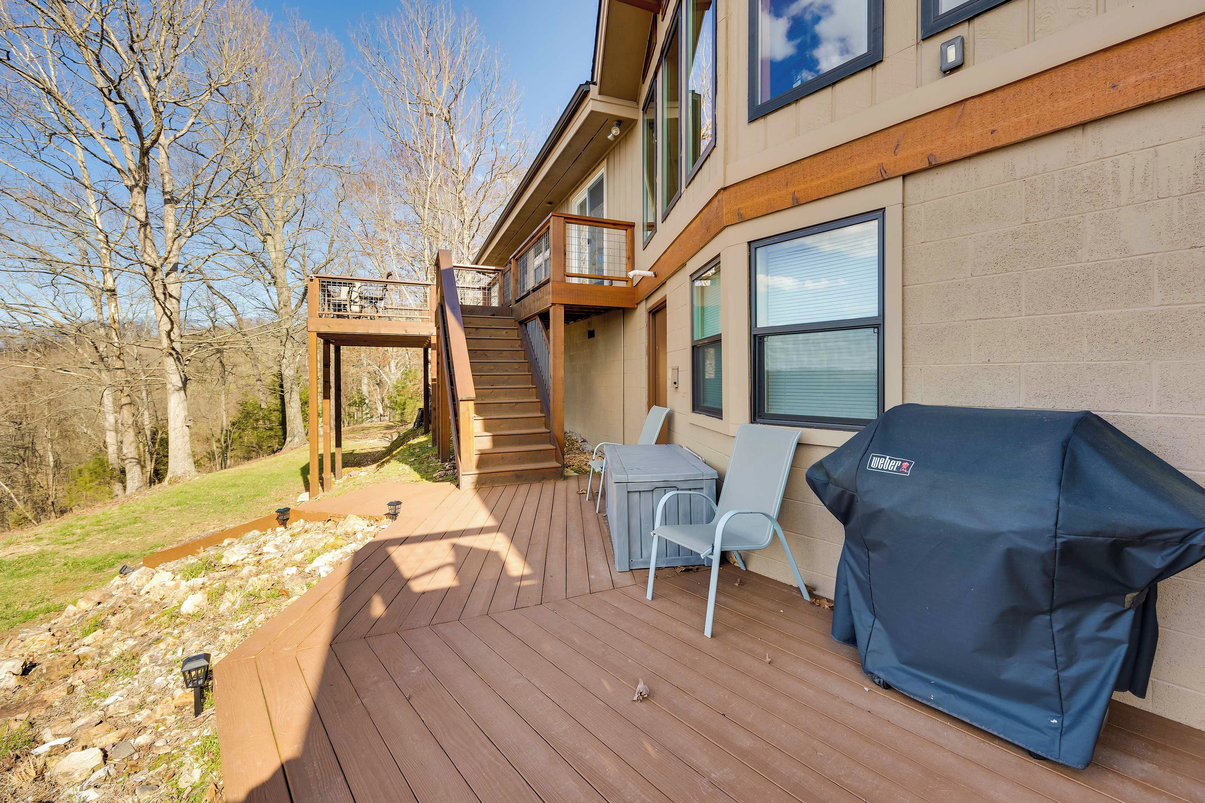 Una terraza con mobiliario exterior, una funda para barbacoa y una escalera que lleva a un nivel superior.