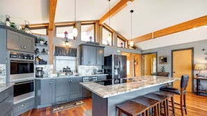 A modern kitchen with grey cabinets, stainless steel appliances, and a large island with bar stools.