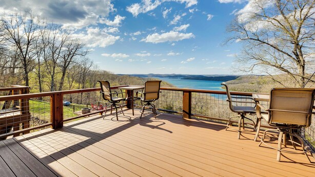 A wooden deck with outdoor seating and a view of a lake.