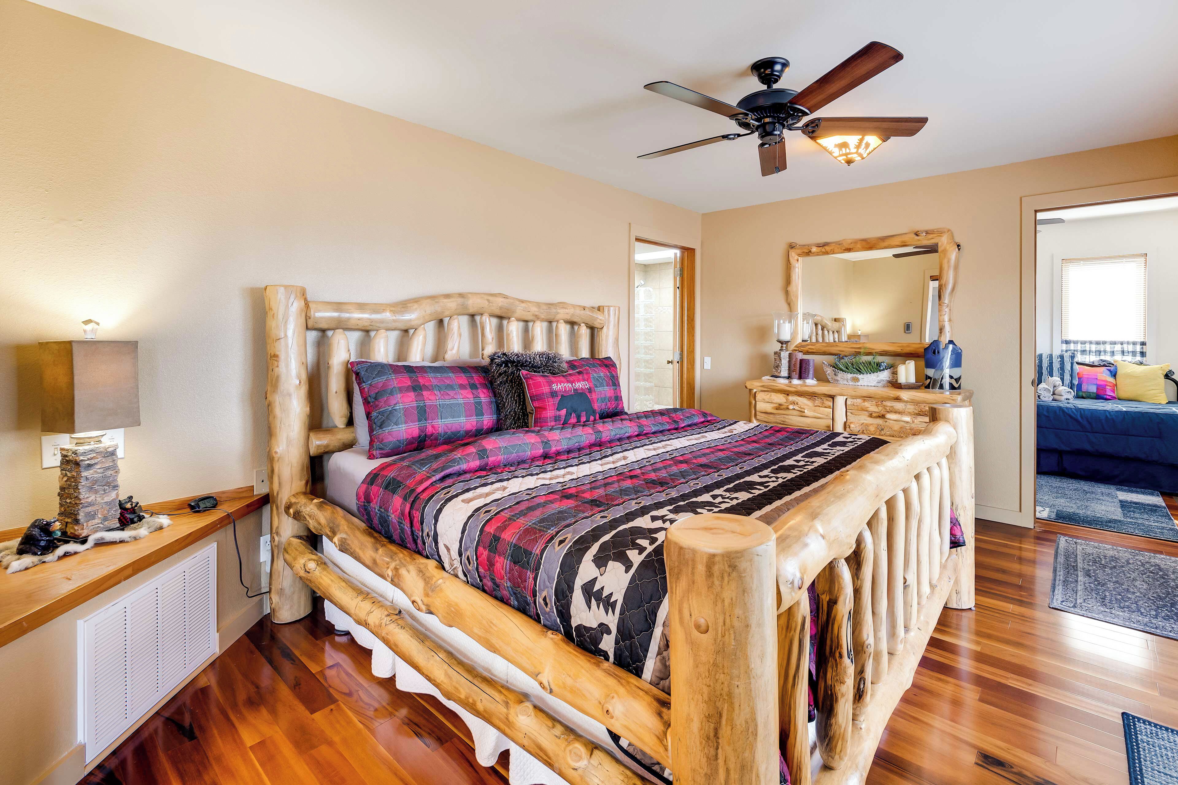 Una cama de madera rústica con cabecera, ventilador de techo y mesita de noche con lámpara.