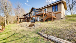 A large, modern house with multiple levels, a wooden deck, and a staircase leading to the upper floor.