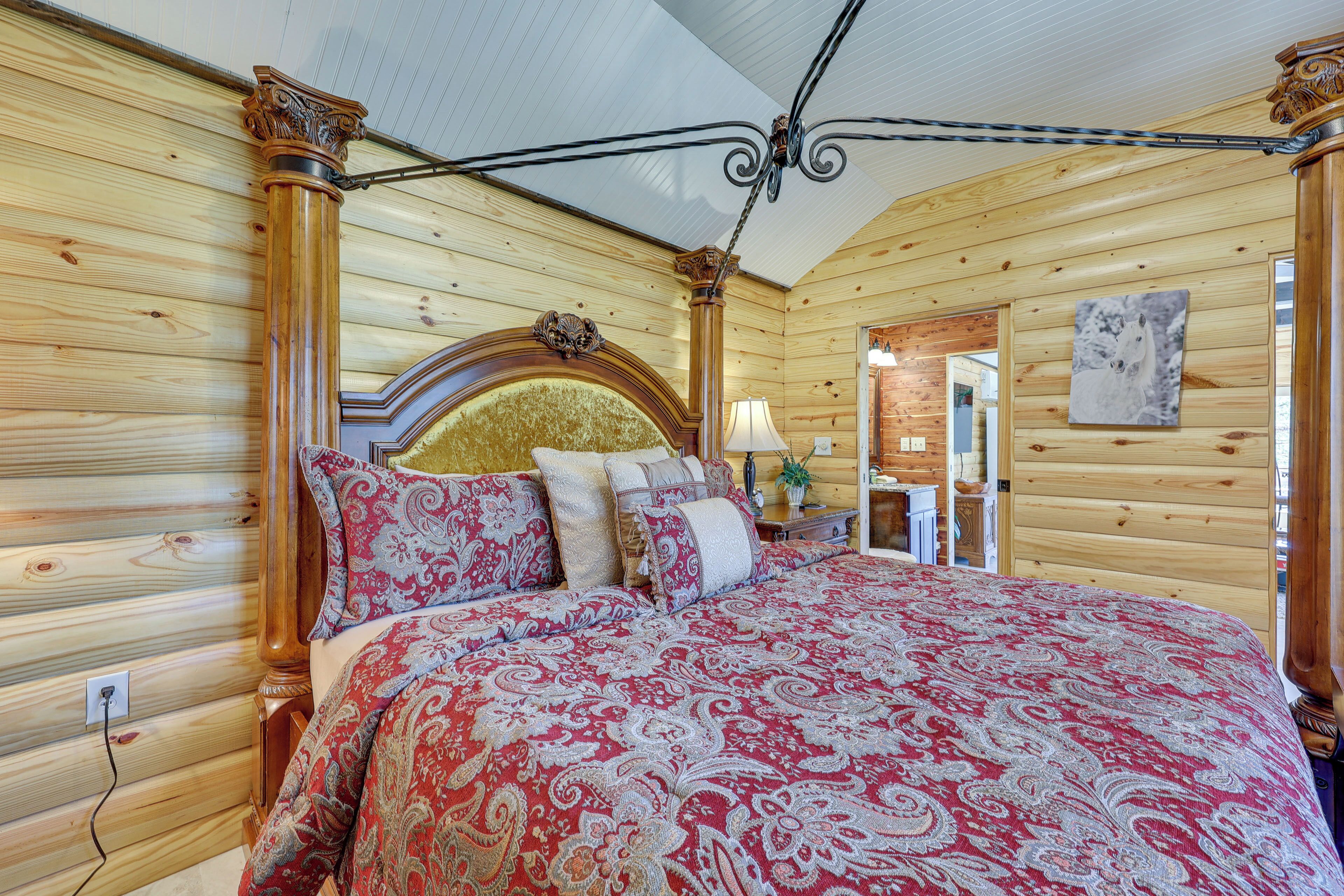 A wooden-paneled bedroom with a large bed, a wooden headboard, and a ceiling fan.