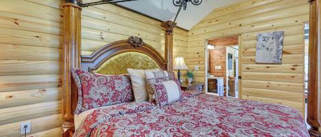 A wooden-paneled bedroom with a large bed, a wooden headboard, and a ceiling fan.