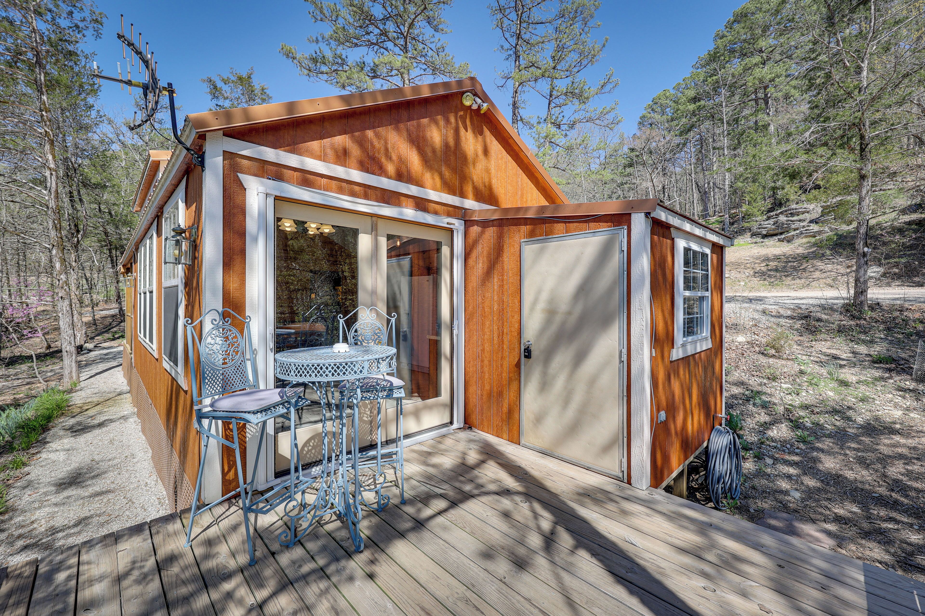 A wooden cabin with a patio, a table, and chairs.
