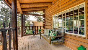 A wooden porch with a swing seat and a large window. - Pine Mountain Club Cabin w/ Community Pool! (Pine Mountain Club)