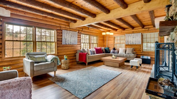 A log cabin interior with a cozy living area featuring a sofa set, a fireplace, and large windows. - Pine Mountain Club Cabin w/ Community Pool! (Pine Mountain Club)