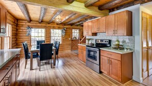 A log cabin interior with a dining area, kitchen, and wooden ceiling beams. - Pine Mountain Club Cabin w/ Community Pool! (Pine Mountain Club)