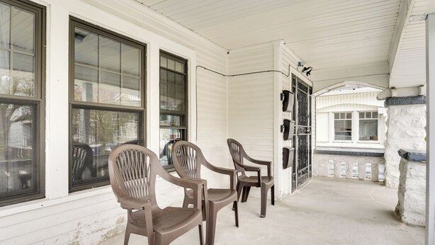 A covered porch with three plastic chairs, white siding, and a stone wall. - Buffalo Vacation Rental ~ 20 Mi to Niagara Falls! (Buffalo)