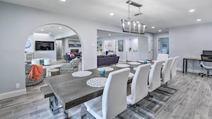 A modern dining area with a long table, white chairs, and a chandelier. - Luxury Granbury Home w/ Private Boat Dock! (Granbury)