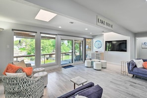 A spacious living room with large windows, a fireplace, and a sign reading "LAKE HOUSE". - Luxury Granbury Home w/ Private Boat Dock! (Granbury)