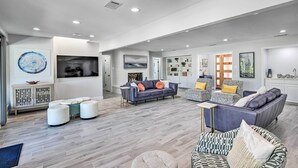 A spacious living room with a large sofa, ottomans, and a fireplace. - Luxury Granbury Home w/ Private Boat Dock! (Granbury)