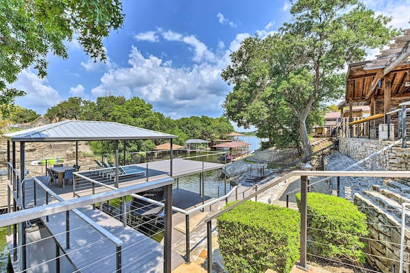 A waterfront property with a wooden deck, outdoor seating, and a stone staircase.