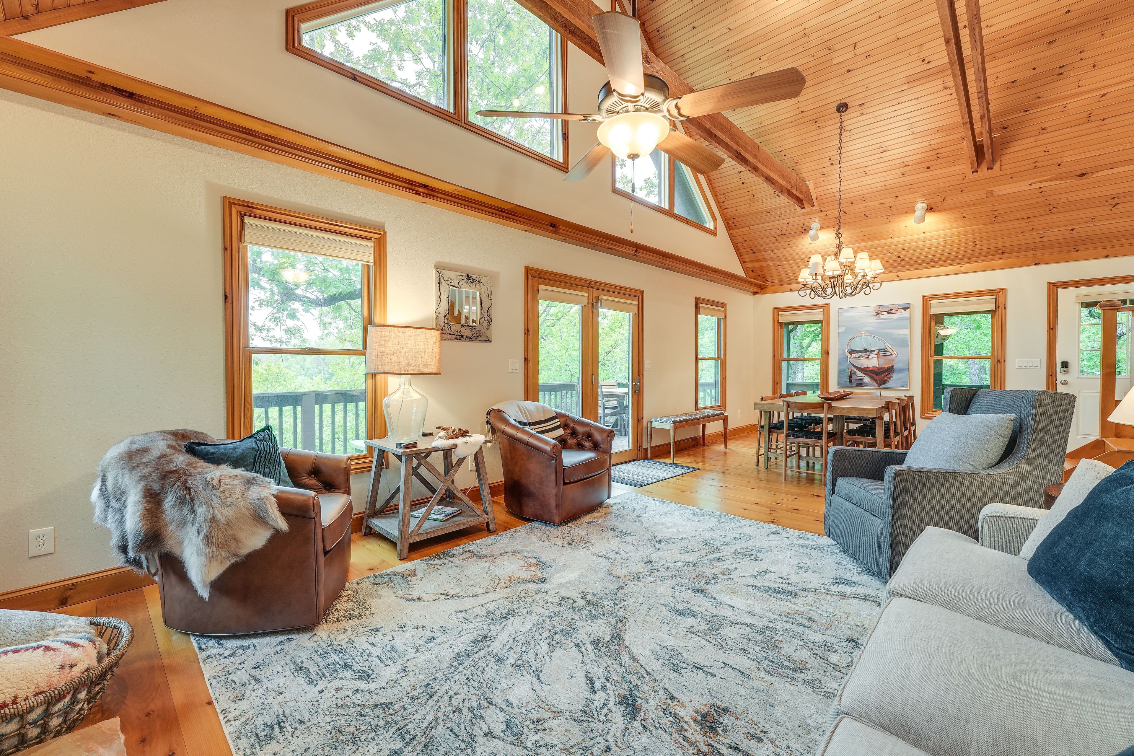 A spacious living room with a high ceiling, large windows, and a chandelier.