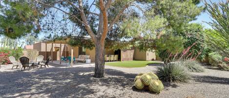 A patio area with outdoor seating, a tree, and a cactus.