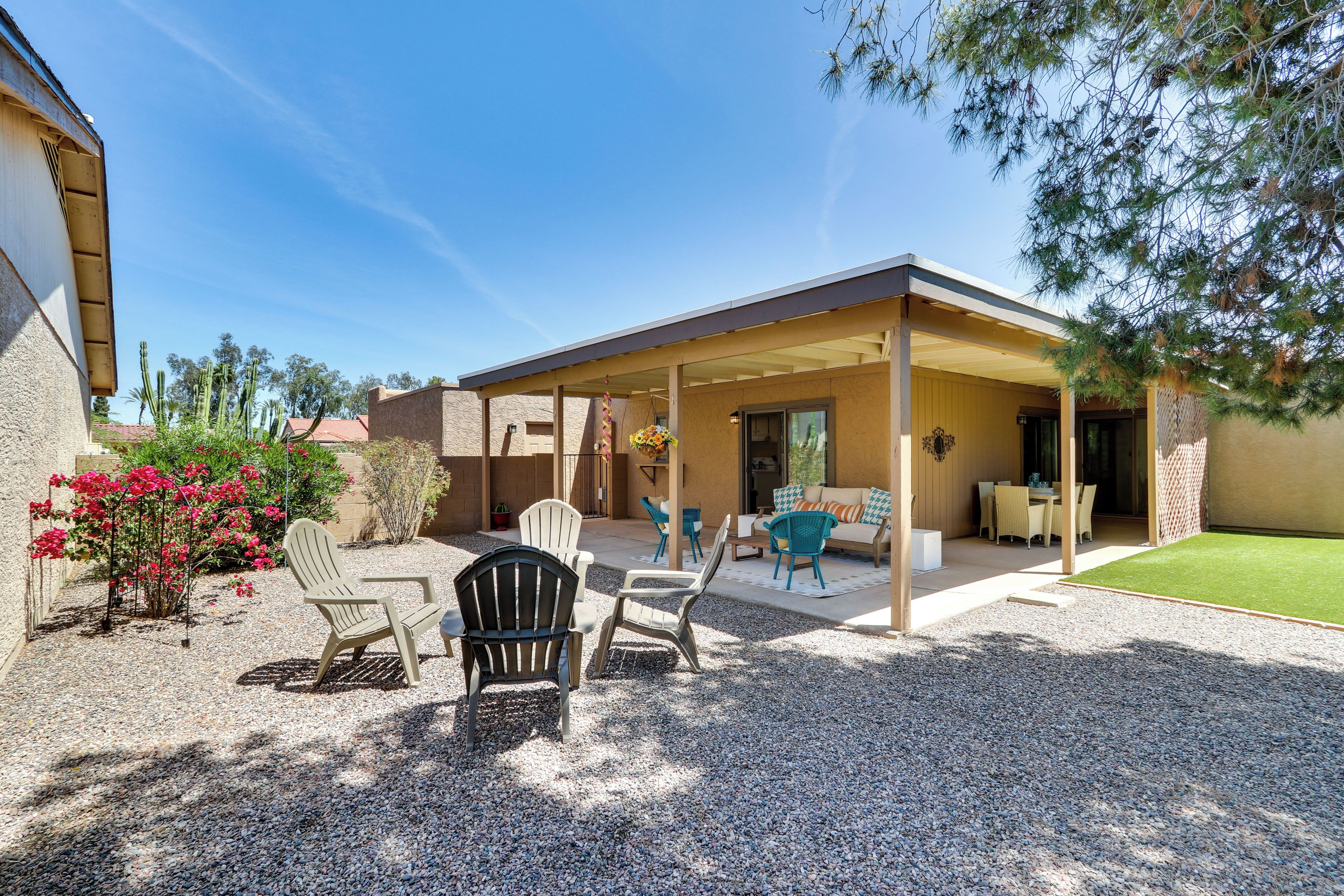 A covered patio area with outdoor seating, including chairs and tables, and a small lawn.