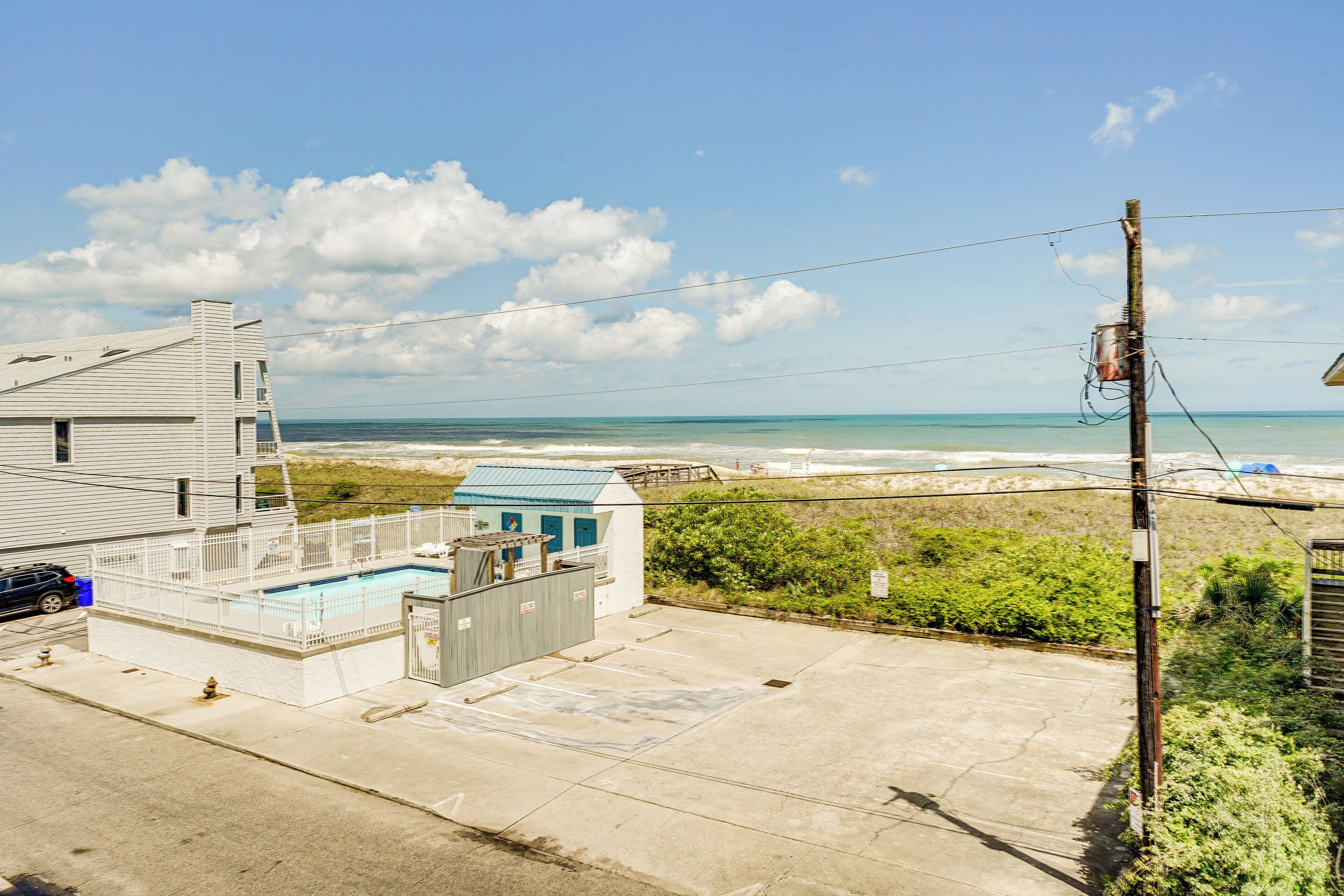 A residential area with a swimming pool, a beach, and a clear sky.