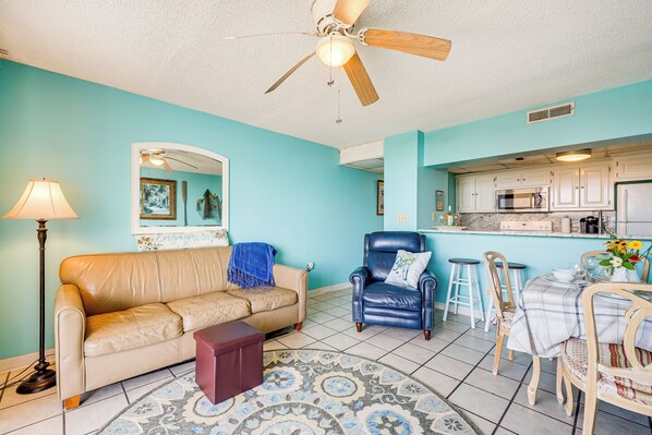 A living room with a beige sofa, a blue armchair, a coffee table, and a patterned rug.
