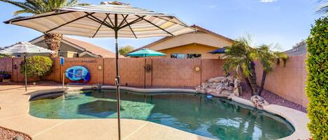 A swimming pool with a curved edge, surrounded by a brick wall and palm trees.