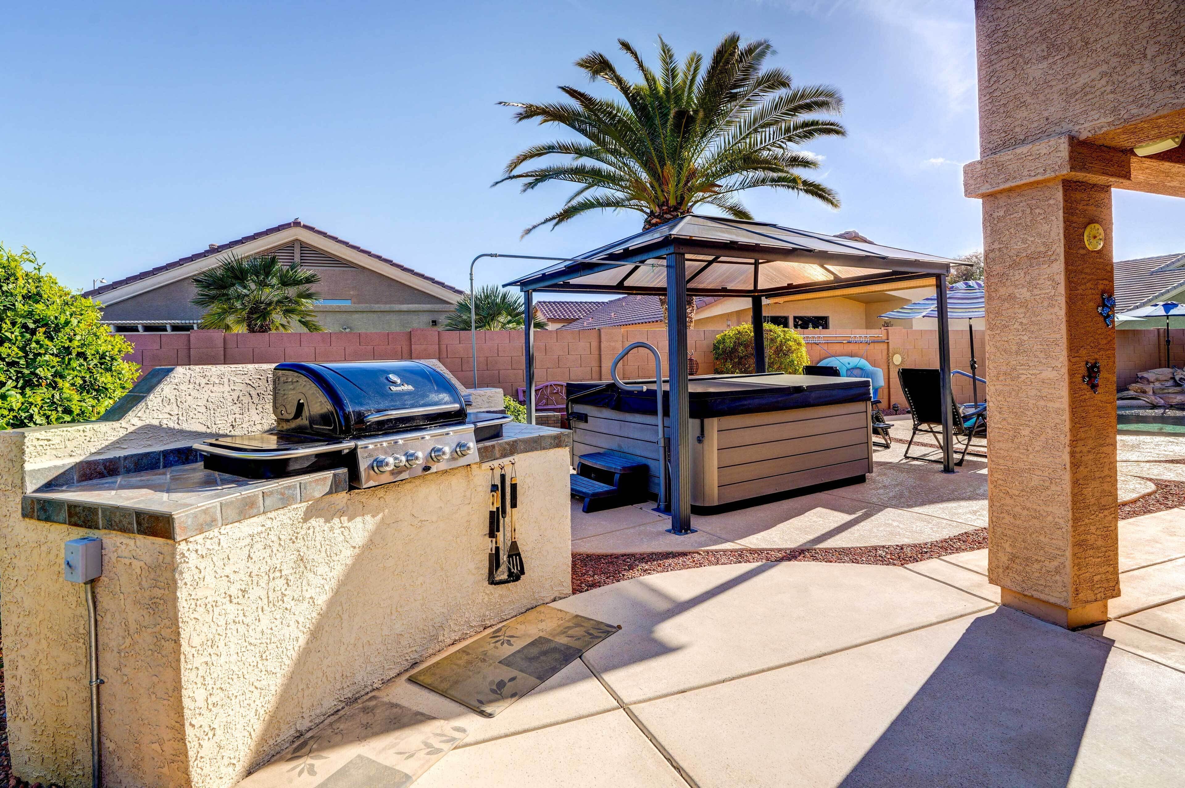 An outdoor kitchen area with a grill, a covered seating area, and a palm tree.