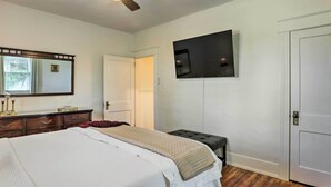 Une chambre à coucher avec un lit, une commode, un téléviseur et deux portes.