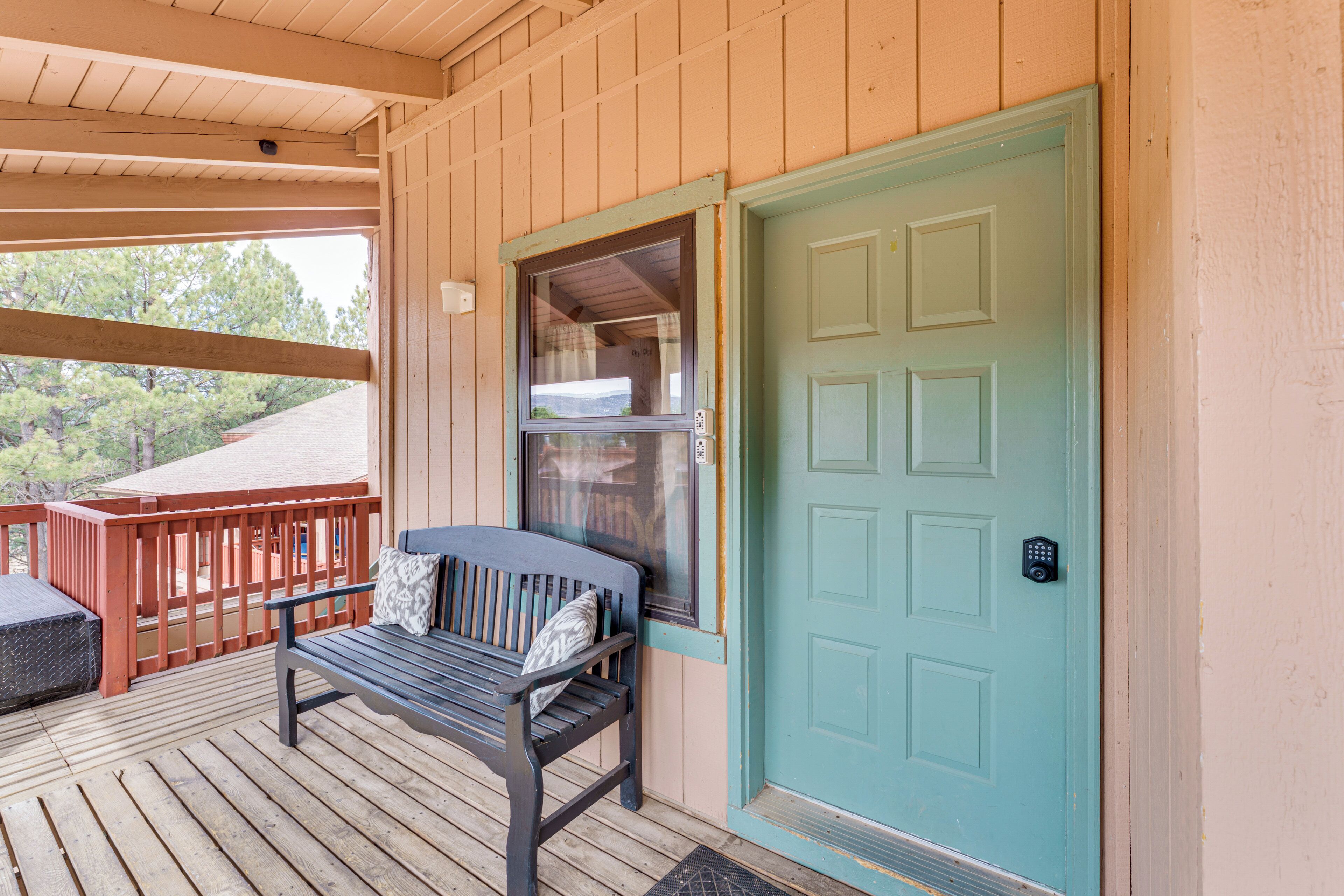 A wooden deck with a bench and a teal door with a window.
