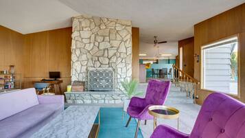 A living room with a stone wall, purple chairs, a sofa, and a TV.