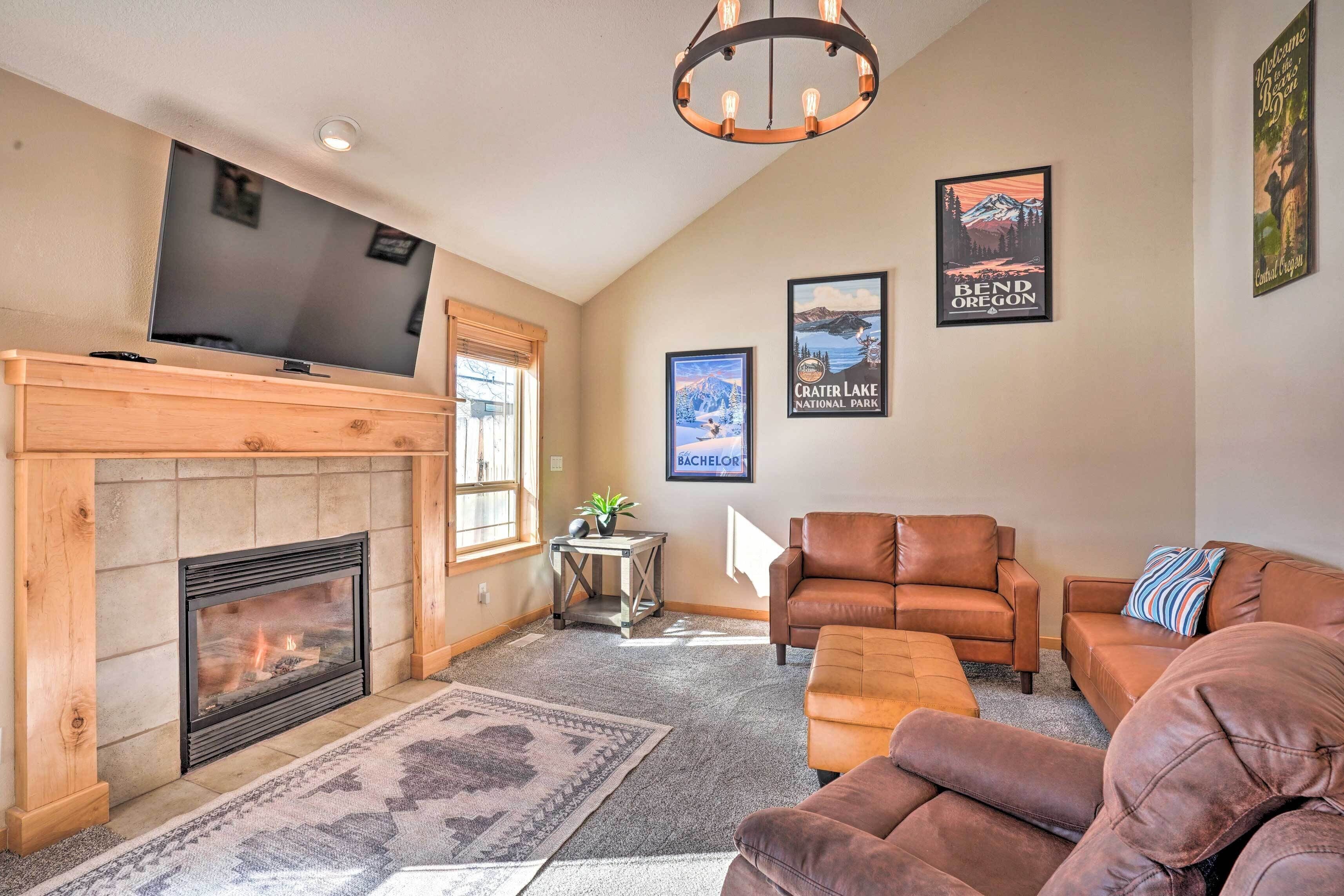 A living room with a fireplace, leather sofas, a television, and framed pictures on the wall.